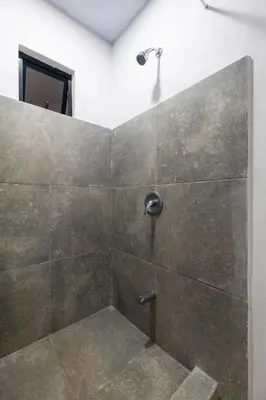 a bathroom with a shower with a stone wall at Zen Studio in Jacó