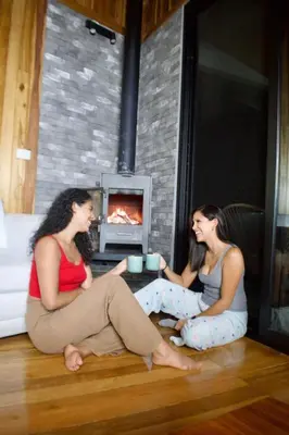 two women sitting on the floor in front of a fireplace at Casa horizonte Verde in Sierra