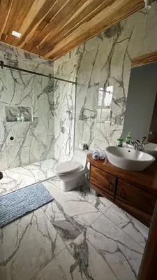 a marble bathroom with a sink and a toilet at Casa horizonte Verde in Sierra