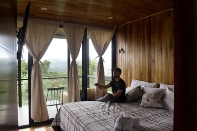 a man sitting on a bed in a room with a window at Casa horizonte Verde in Sierra