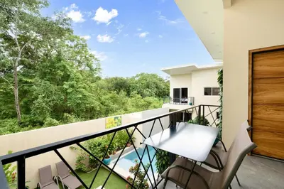 a balcony with a view of a pool and trees at Pierre and Colors TAMARINDO in Tamarindo