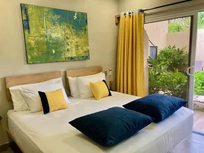 a bed with blue pillows on it with a window at Pierre and Colors TAMARINDO in Tamarindo