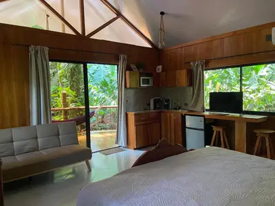 a bedroom with a bed and a kitchen with a desk at Monkey House, Monterrey in San Cristóbal