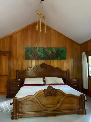 a large wooden bed in a bedroom with wooden walls at Monkey House, Monterrey in San Cristóbal
