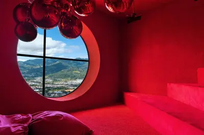 a red room with a round window and a bed at Studio en piso 29 Secrt Sabana in San José