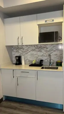 a kitchen with white cabinets and a sink and a microwave at Studio en piso 29 Secrt Sabana in San José