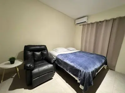 a bedroom with a bed and a leather chair at bambu house in Alajuela City