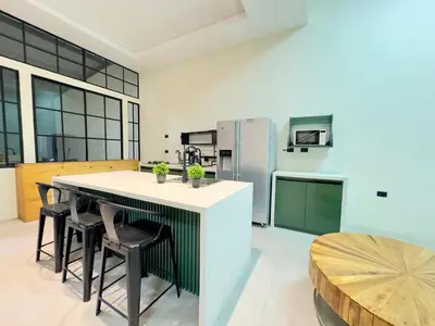 a kitchen with a counter with chairs and a refrigerator at bambu house in Alajuela City
