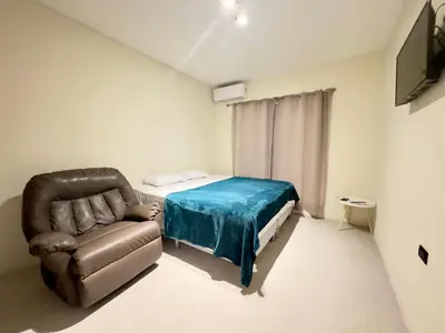 a bedroom with a bed and a couch and a chair at bambu house in Alajuela City