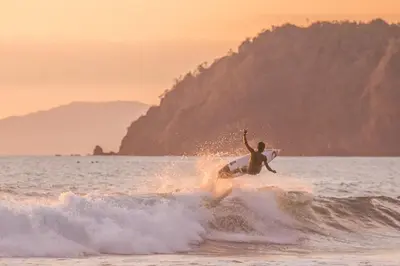 a man riding a wave on a surfboard in the ocean at Spectacular 3 bedroom Penthouse at Crocs Resort Casino in Jacó