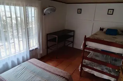 a bedroom with a bed and a table and windows at Orange Hills -Atenas- in Barrio Jesús