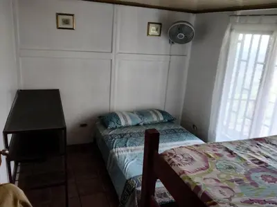 a bedroom with two beds and a table and a fan at Orange Hills -Atenas- in Barrio Jesús