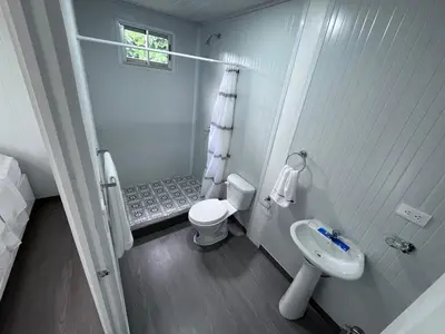 a white bathroom with a toilet and a sink at Cautiva Sleep Inn in Guácimo