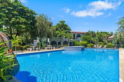 a large blue swimming pool with trees and a building at Casa Verde 2b2b Completely Renovated Ground Unit in Coco