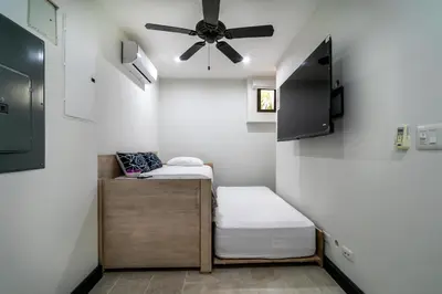 a small room with two beds and a ceiling fan at Calle La Ronda 18 At Las Catalinas in Playa Danta