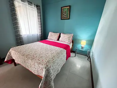 a small bedroom with a bed with a pink blanket at Apartamento en Manuel Antonio in Quepos