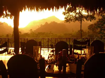 a table set up for a meal with the sunset in the background at Rafiki Safari Lodge in Savegre