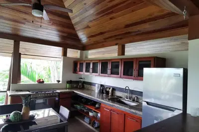 a kitchen with wooden ceilings and a white refrigerator at Casita Morpho, high speed wifi in Uvita