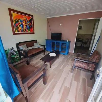 a living room with couches a table and a tv at The garden suite in Alajuela City