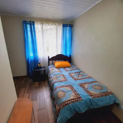a bedroom with a bed and blue curtains and a window at The garden suite in Alajuela City