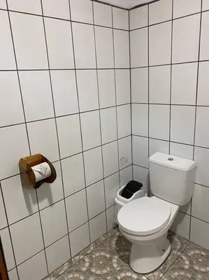 a bathroom with a toilet in a white tiled wall at Cabina vista al valle Monteverde in Monteverde Costa Rica