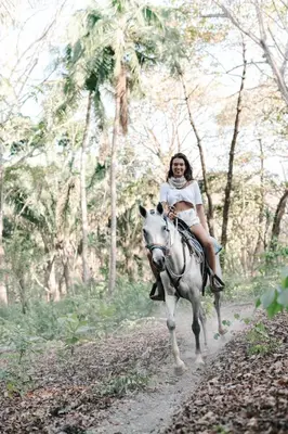 a woman riding a horse down a dirt road at Star Mountain Jungle Lodge - Only 4x4 Vehicles, No Meals in Mal País