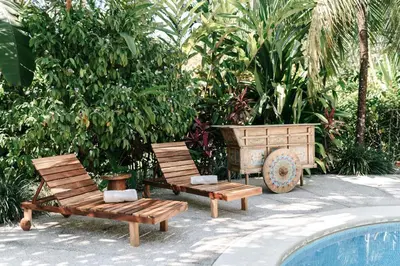 two wooden chairs sitting next to a swimming pool at Star Mountain Jungle Lodge - Only 4x4 Vehicles, No Meals in Mal País