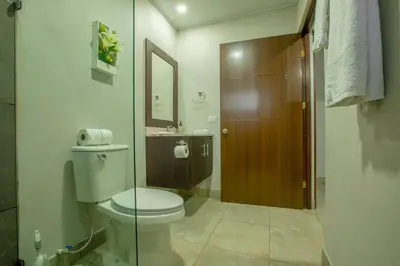 a bathroom with a toilet and a glass door at Villa Margarita - Families Getaway in La Fortuna in Fortuna