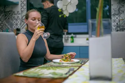 a woman sitting at a table drinking a glass of wine at Villa Margarita - Families Getaway in La Fortuna in Fortuna