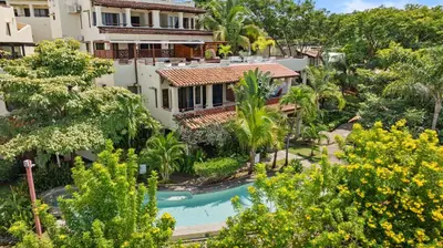 an aerial view of a resort with a pool and trees at Sunshine Escape with a Rooftop Patio in Coco