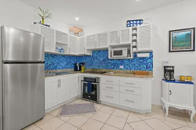 a kitchen with white cabinets and a stainless steel refrigerator at Sunshine Escape with a Rooftop Patio in Coco