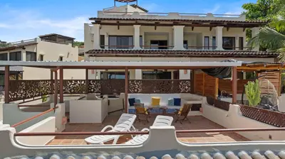a balcony with white chairs and a house at Sunshine Escape with a Rooftop Patio in Coco