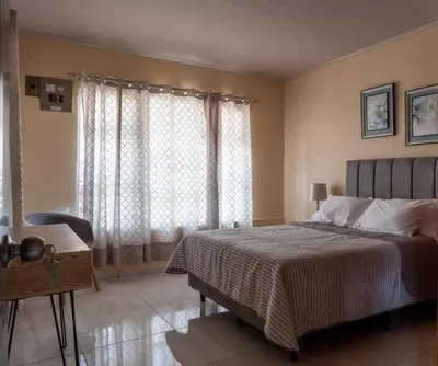a bedroom with a bed and a desk and a window at Villa Paz in San José