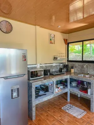 a kitchen with a refrigerator and a clock on the wall at Cabaña Timarama in Fortuna