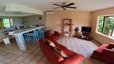 a living room with red couches and a kitchen at Casa Vista Pacifico in Esterillos