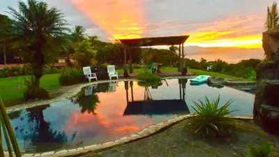 a swimming pool with two chairs and a gazebo at Casa Vista Pacifico in Esterillos