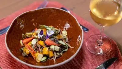 a bowl of salad next to a glass of wine at Tocu Tent Camp in Caño Negro
