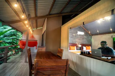 a man sitting at a table in a room with a laptop at Valverde Glamping & Ecolodge in Tortuguero