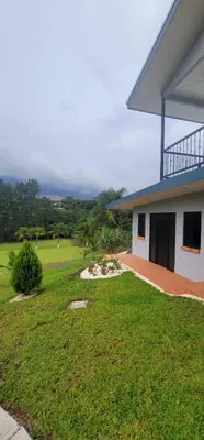 a house with a grassy yard next to a building at La Piedra in Alajuela City