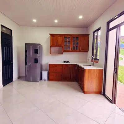 a kitchen with wooden cabinets and a stainless steel refrigerator at La Piedra in Alajuela City