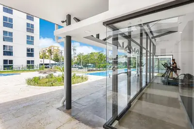 an open glass door of a building with a pool at Upstay - 3BR New Condo in Jaco 5mins to Beach in Jacó