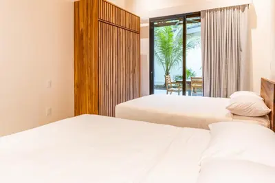 two beds in a bedroom with a view of the ocean at Coco Nosara Villas Guiones Family Resort Casa José in Nicoya