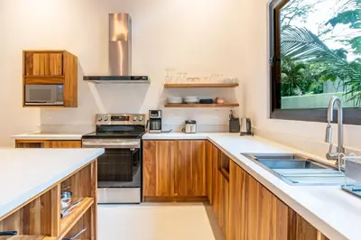 a kitchen with wooden cabinets and a window at Coco Nosara Villas Guiones Family Resort Casa José in Nicoya