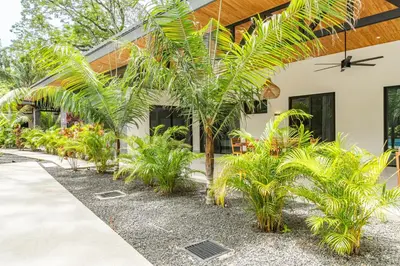 a house with palm trees in front of it at Coco Nosara Villas Guiones Family Resort Casa José in Nicoya