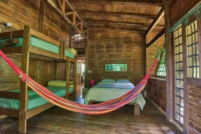 a hammock in a room with a bed in it at Finca Anjala - Architectural lodge on sustainable in Ojochal