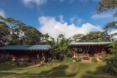 a building with a blue roof with tables and chairs at Finca Anjala - Architectural lodge on sustainable in Ojochal