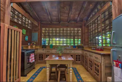 a kitchen with wooden cabinets and a table in it at Finca Anjala - Architectural lodge on sustainable in Ojochal