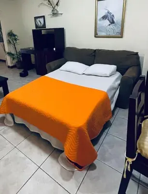 a bedroom with a bed with an orange blanket at Casa de Romá in Coco