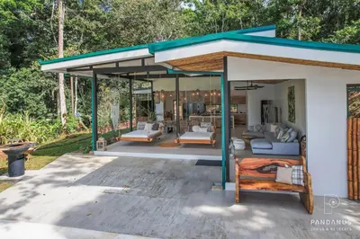 a guest house with a porch with two beds at Pandanus Lodge & Retreats Bungalow Heliconia in Cariblanco