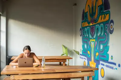 a woman sitting at a table with a laptop at Argdivan Beach Hostel in Sámara